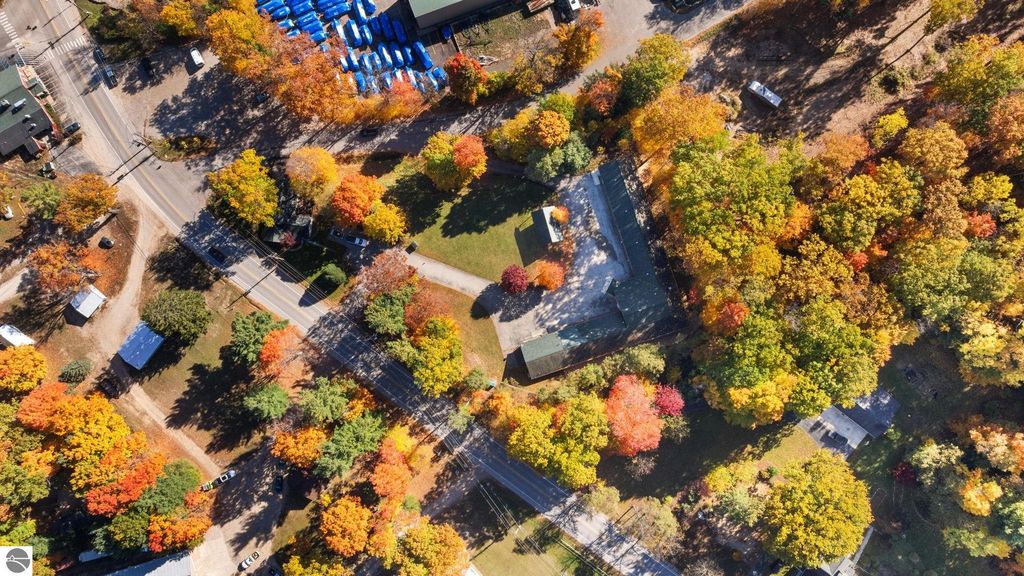 Aerial view of vibrant fall foliage surrounding 12800 & 12862 Cherry Avenue, Rapid City, MI, showcasing tree-lined roads and nearby properties, emphasizing the scenic location near Torch Lake.