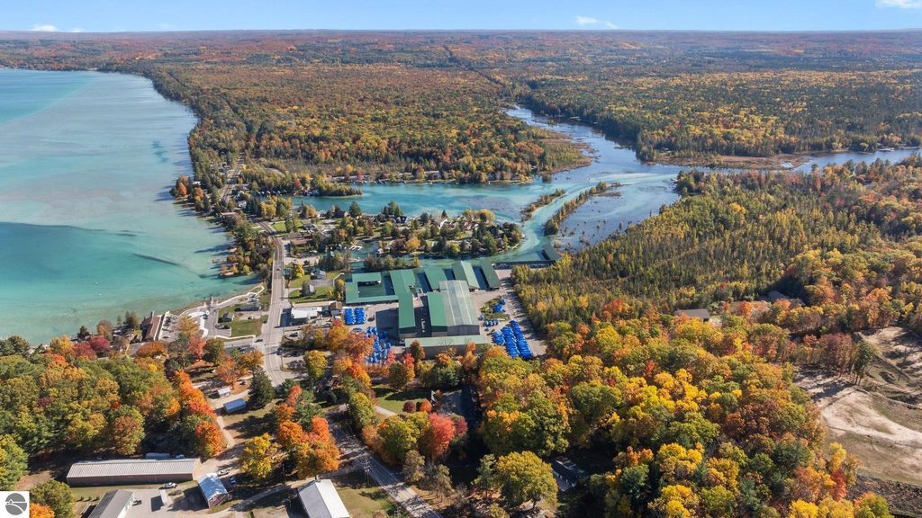 Aerial view of Torch Lake area in Northern Michigan, showcasing vibrant fall foliage, waterfront properties, and proximity to recreational opportunities, relevant to the resort property listing at 12800 & 12862 Cherry Avenue, Rapid City, MI.