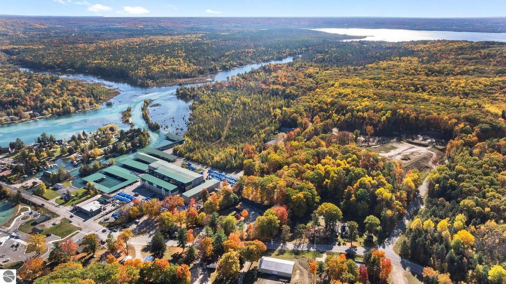 Aerial view of resort property at 12800 & 12862 Cherry Avenue, surrounded by colorful autumn foliage, featuring motel buildings and nearby waterways in Rapid City, MI.