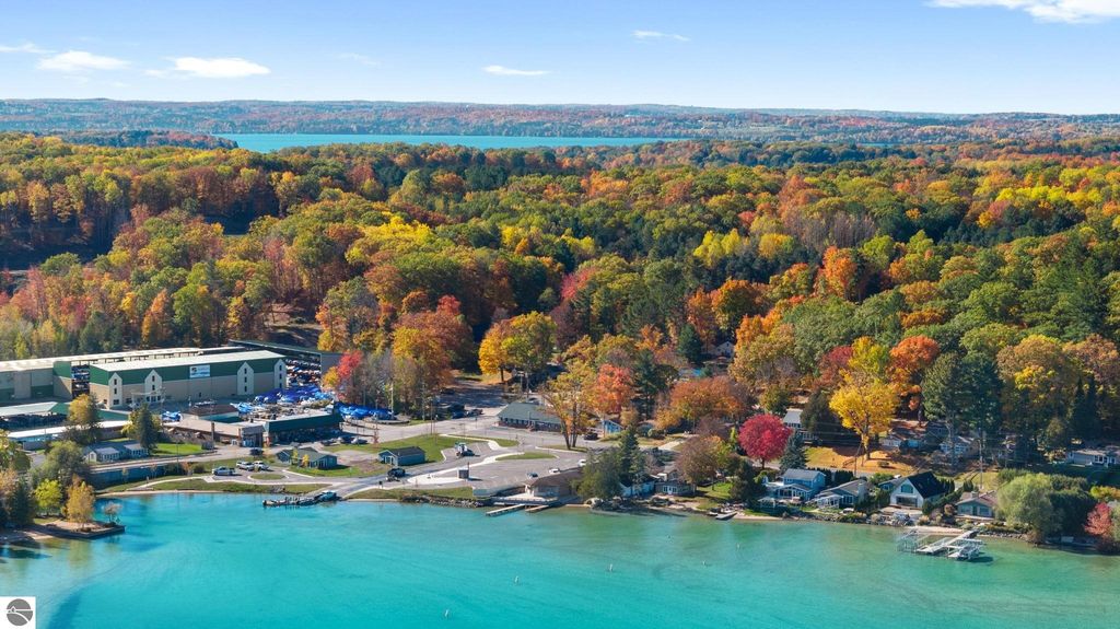 Aerial view of Torch Lake area in Northern Michigan, showcasing vibrant autumn foliage, waterfront properties, and a resort complex, highlighting the region's natural beauty and investment potential.