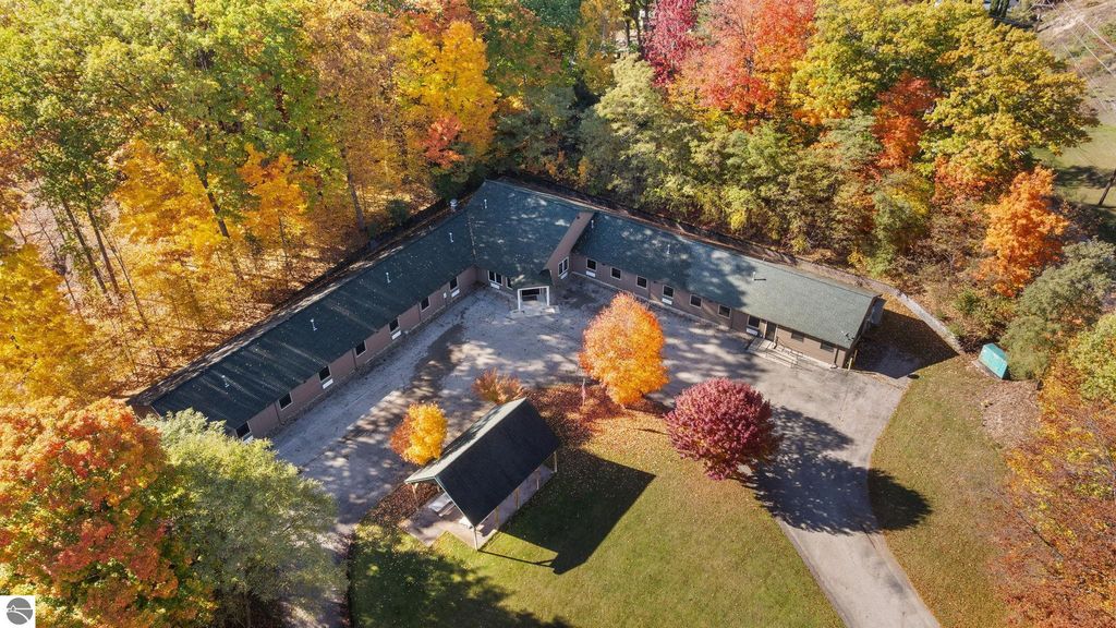 Aerial view of a resort property featuring a 14-unit motel surrounded by vibrant autumn foliage, located at 12800 & 12862 Cherry Avenue, Rapid City, MI, highlighting potential for investment and rental income.