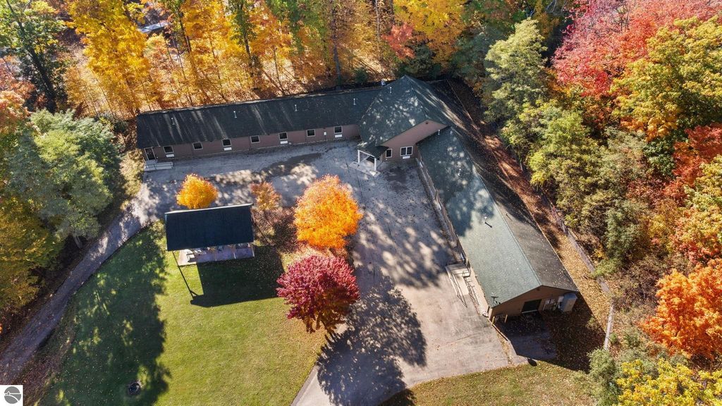 Aerial view of a resort property featuring a 14-unit motel and a home, surrounded by vibrant autumn foliage, highlighting potential for investment near Torch Lake, Rapid City, MI.