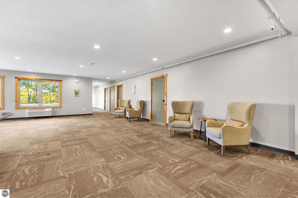 Spacious lobby area of a motel featuring two armchairs and large windows overlooking trees, designed for guest relaxation and comfort.