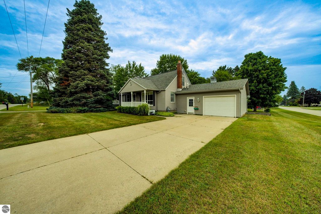 Well-maintained single-family home at 624 Fenton Street, Kingsley, MI, featuring a covered front porch, large driveway, and surrounding greenery.