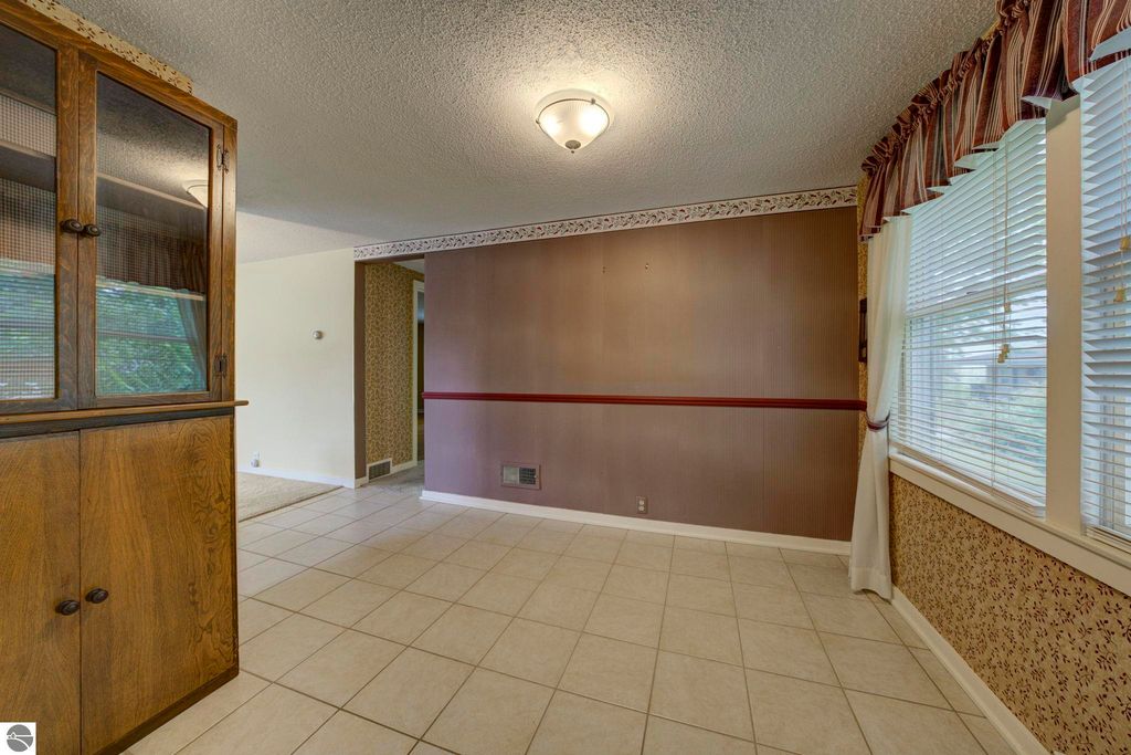 Interior view of a well-maintained living space featuring tiled flooring, built-in cabinets, and natural light from windows, showcasing the open concept layout of the home at 624 Fenton Street, Kingsley, MI.