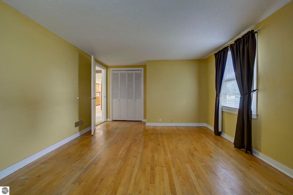 Living room in a well-maintained 1 1/2 story home at 624 Fenton Street, featuring hardwood floors, yellow walls, and natural light from windows with curtains.
