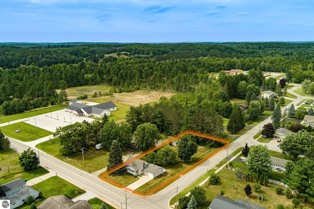 Aerial view of 624 Fenton Street, Kingsley, MI, showcasing the well-maintained 1 1/2 story home on a double lot, surrounded by greenery and nearby residential areas, emphasizing its corner location at Fenton and Pearl Street.