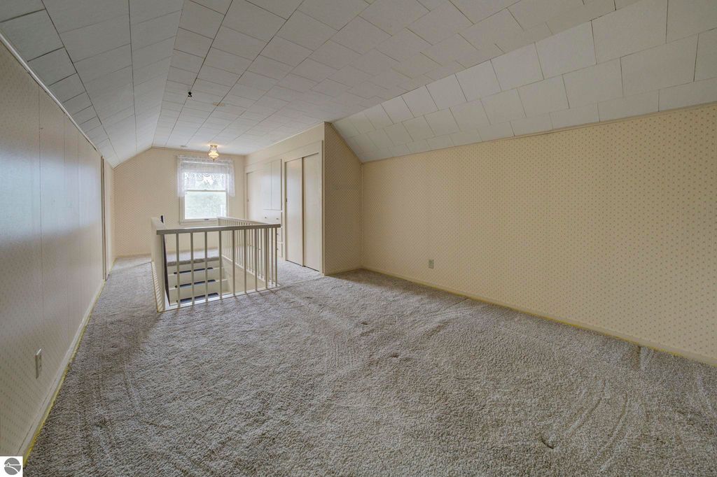Spacious upstairs den area in a well-maintained 1 1/2 story home at 624 Fenton Street, featuring plush carpeting, natural light from a window, and built-in cabinets, ideal for additional living space or a third bedroom.