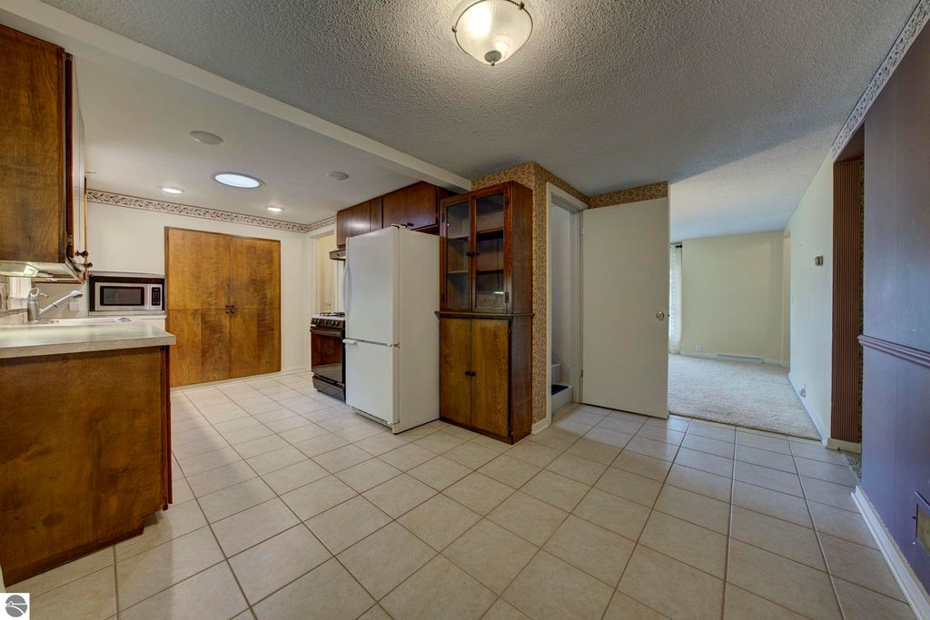 Kitchen and dining area of a well-maintained 1 1/2 story home at 624 Fenton Street, featuring wooden cabinetry, tile flooring, and an open layout connecting to the living room.
