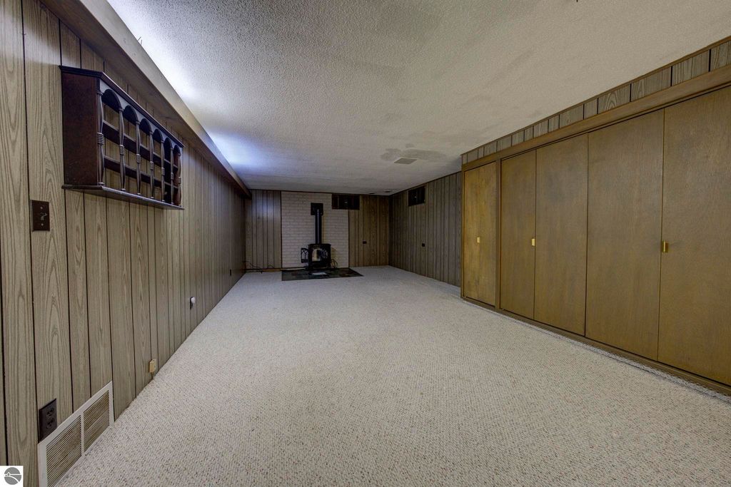Large rec-room with a brick fireplace, built-in cabinets, and ample storage space in the basement of a well-maintained home at 624 Fenton Street, Kingsley, MI.