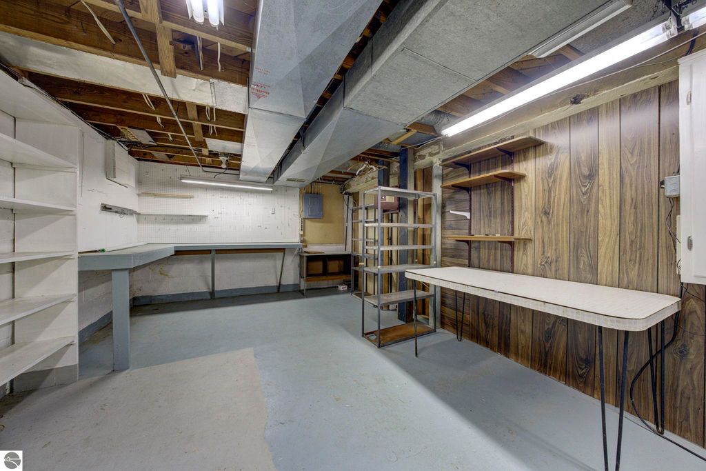 Basement storage area featuring shelving, workbench, and built-in cabinets, showcasing functional space for crafts or a workshop in a Kingsley, MI home listing.