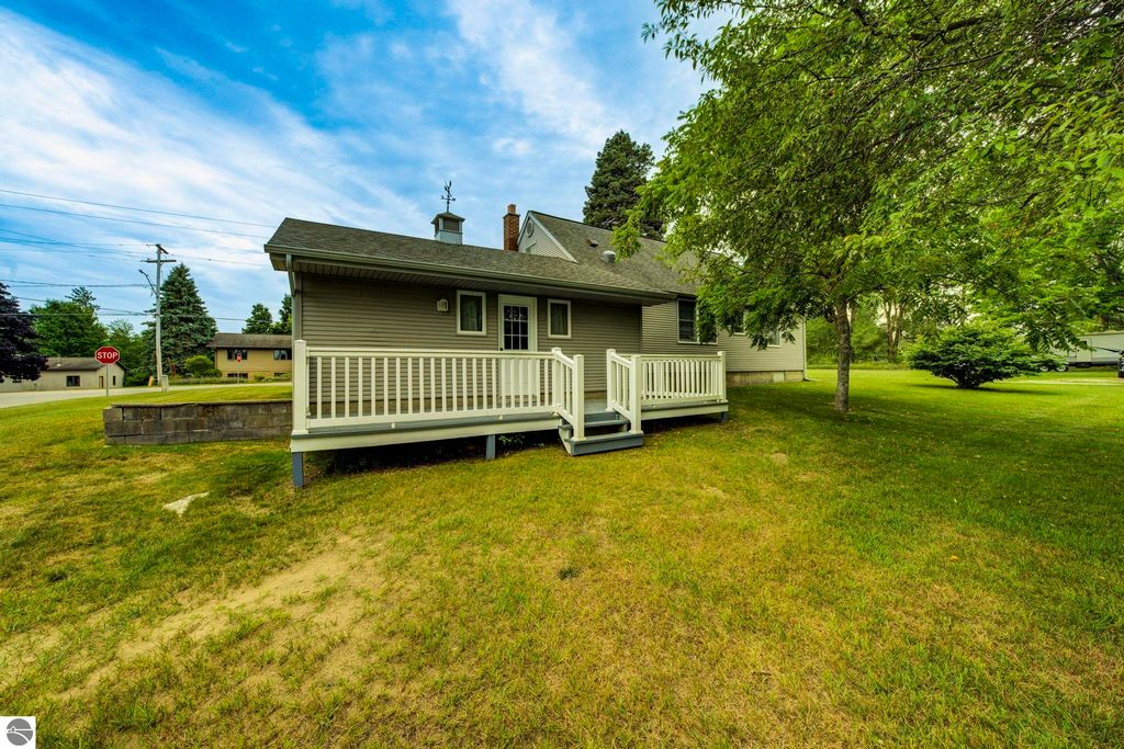 Well-maintained 1.5-story home at 624 Fenton Street, featuring a covered front porch, surrounded by green lawn and trees, located in Kingsley, MI.