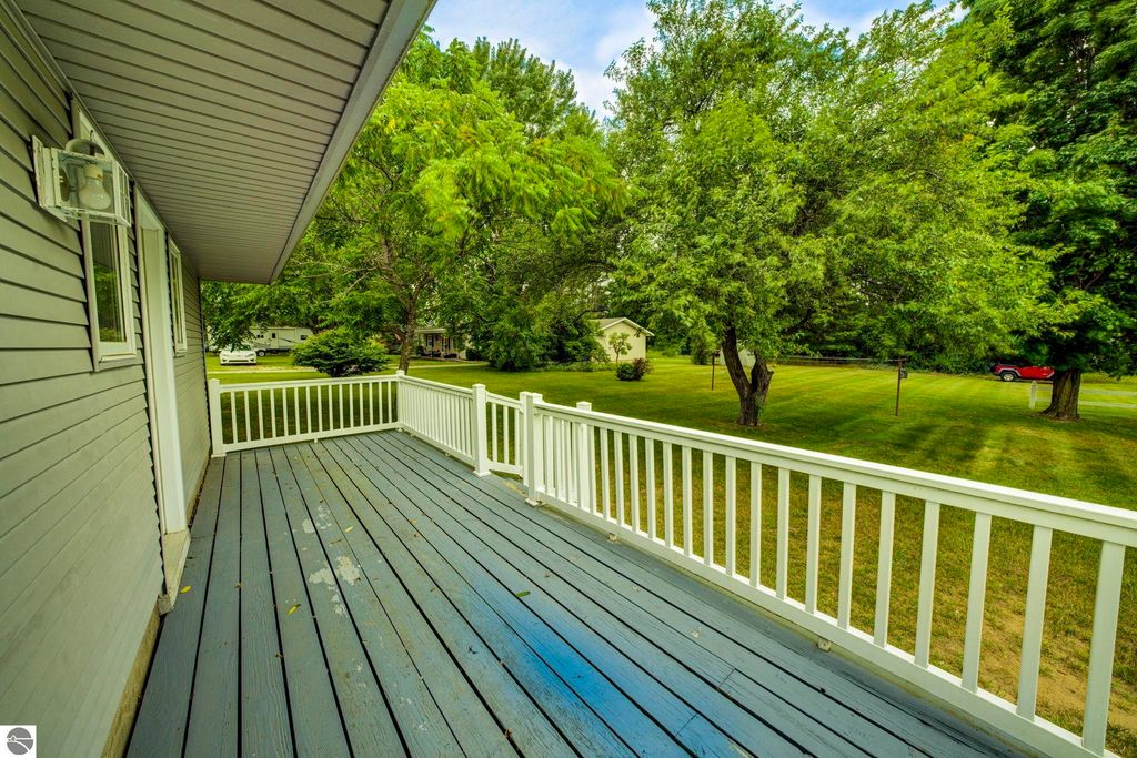 Covered front porch view of 624 Fenton Street, showcasing the spacious deck and surrounding greenery in Kingsley, MI.