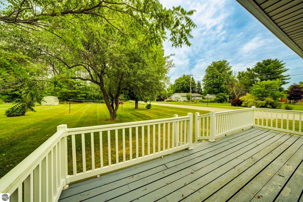 View from the covered front porch of 624 Fenton Street, featuring a spacious yard with trees and a clear sky, showcasing the home's inviting outdoor space in Kingsley, MI.