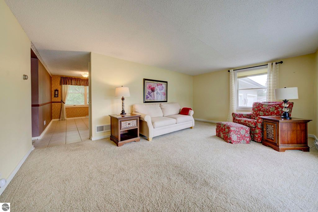 Inviting living room in a well-maintained home at 624 Fenton Street, featuring a beige sofa, floral armchair, and decorative lamp, with natural light from large windows and a cozy atmosphere.
