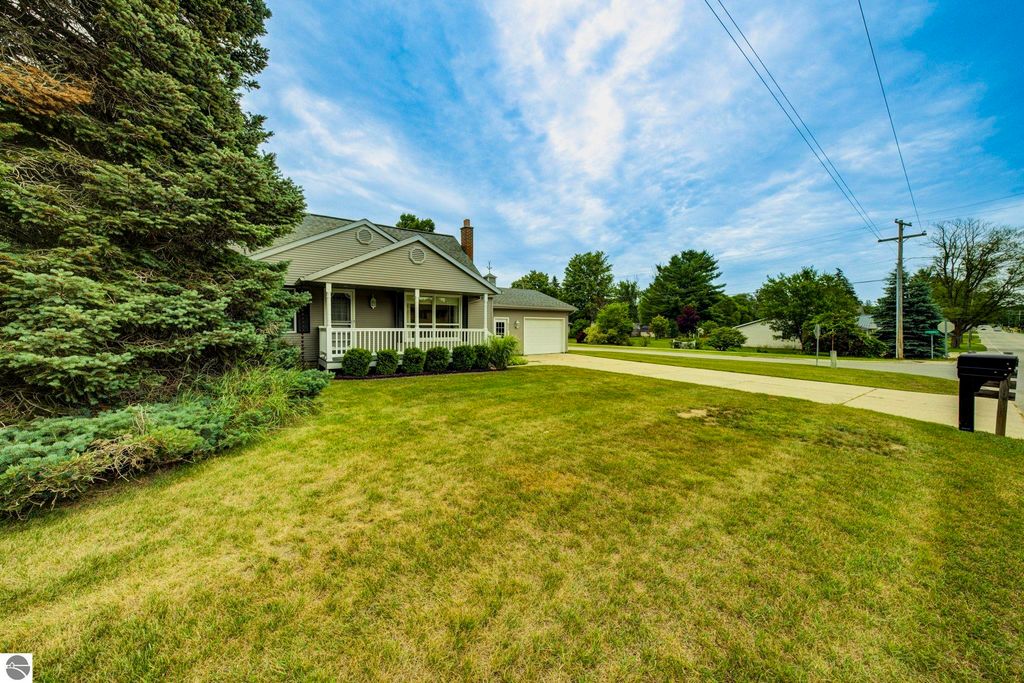 Well-maintained 1 1/2 story home at 624 Fenton Street, featuring a covered front porch, lush green lawn, and nearby roadways in Kingsley, MI.