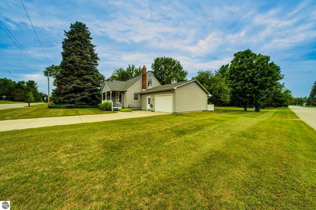 Well-maintained 1 1/2 story home at 624 Fenton Street, Kingsley, MI, featuring a covered front porch, large yard, and surrounding trees.