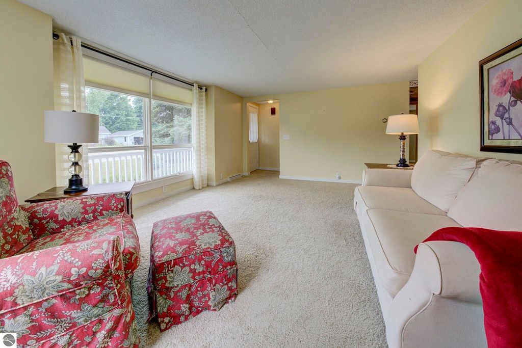 Inviting living room in a well-maintained home at 624 Fenton Street, featuring a floral patterned armchair, a cozy ottoman, and large windows with natural light.