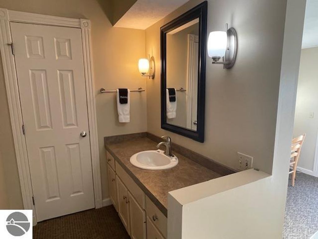 Bathroom vanity area with sink, mirror, and towels in a property listing for 12C Pinnacle Place, Glen Arbor, MI.
