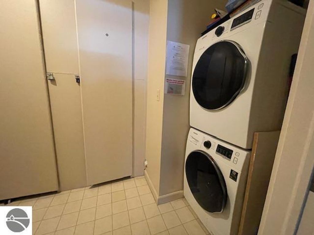 Laundry area featuring stacked washer and dryer units in 12C Pinnacle Place, Glen Arbor, MI, with adjacent closet space.