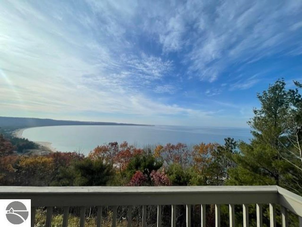 Panoramic view of Lake Michigan and surrounding sand dunes from the balcony of 12C Pinnacle Place, Glen Arbor, MI, showcasing autumn foliage and a clear sky.