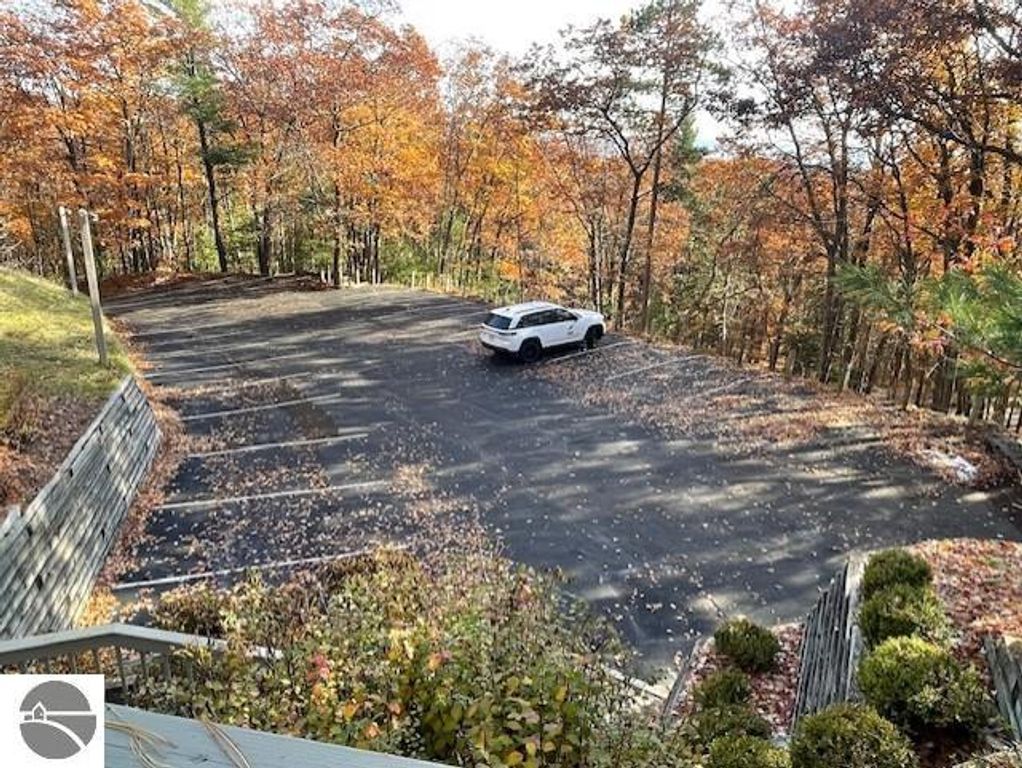 Parking area at Pinnacle Place, surrounded by autumn foliage, featuring a white vehicle, showcasing the scenic location near Lake Michigan in Glen Arbor, MI.