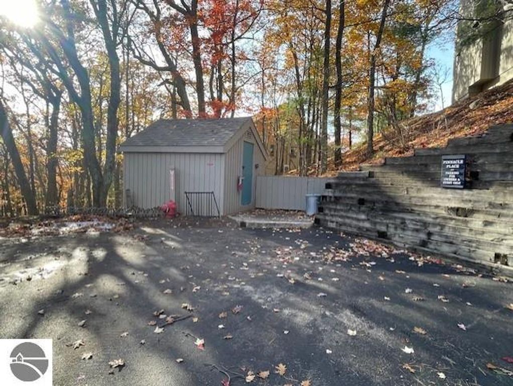 Parking area and shed at Pinnacle Place, Glen Arbor, surrounded by autumn foliage, showcasing natural landscape and property signage.