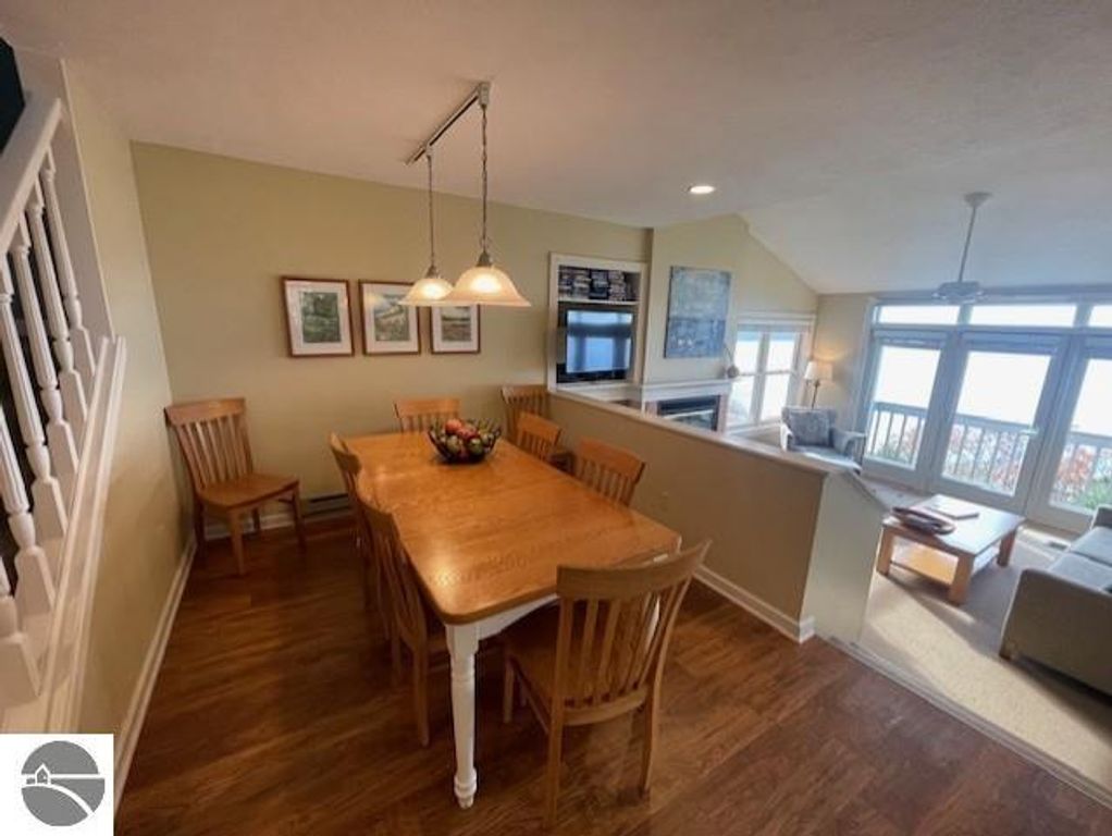 Dining area with wooden table and chairs, overlooking Lake Michigan, featuring a cozy living space with natural light and modern decor at 12C Pinnacle Place, Glen Arbor, MI.