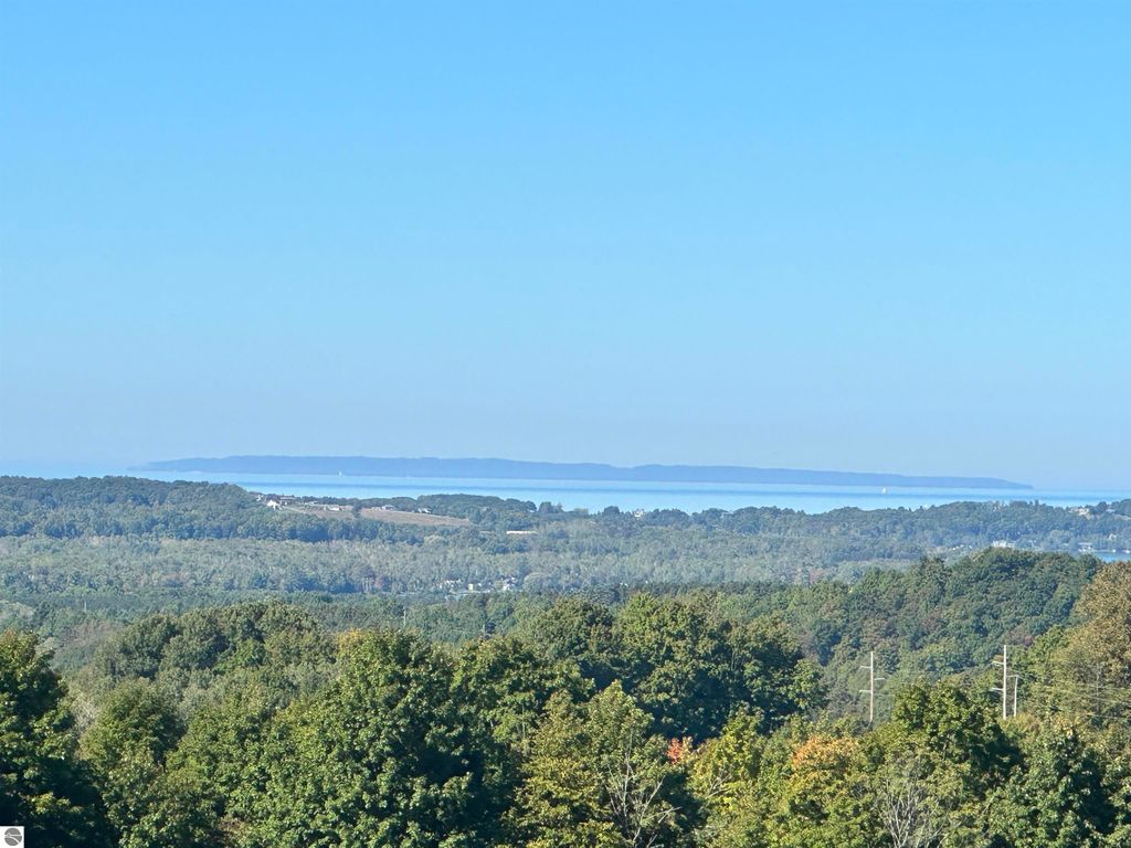 Expansive view from high elevation farmland in Suttons Bay, showcasing Grand Traverse Bay, Lake Michigan, and surrounding lush landscapes.