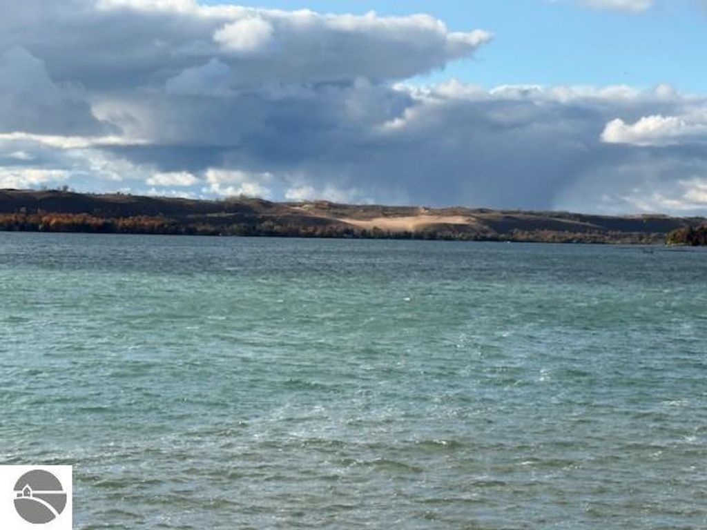 Lake Michigan view with distant dunes and cloudy sky, showcasing the natural beauty near Glen Arbor, MI, ideal for a tranquil retreat.