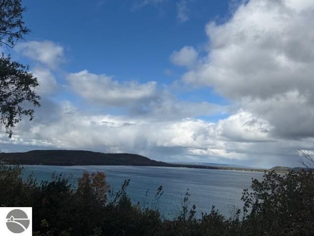 Scenic view of Lake Michigan with cloudy skies and shoreline, showcasing the natural beauty near Glen Arbor, MI, emphasizing the tranquil setting of the property at 6025 Forest Haven Drive.