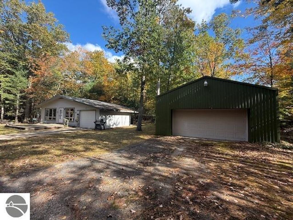 Cozy cottage and green pole building on wooded lot at 6025 Forest Haven Drive, Glen Arbor, MI, surrounded by autumn foliage, ideal for relaxation or vacation rental.