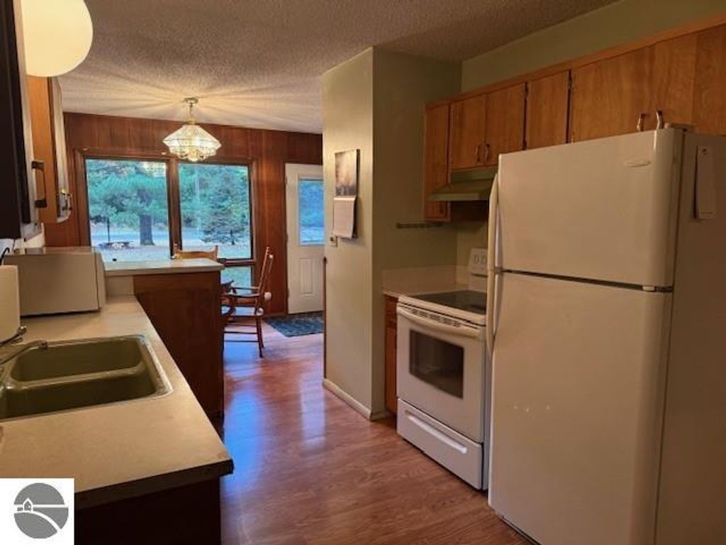 Cozy kitchen interior with green sink, white appliances, and wooden cabinetry, showcasing a welcoming space in the 2-bedroom cottage at 6025 Forest Haven Drive, Glen Arbor, MI.