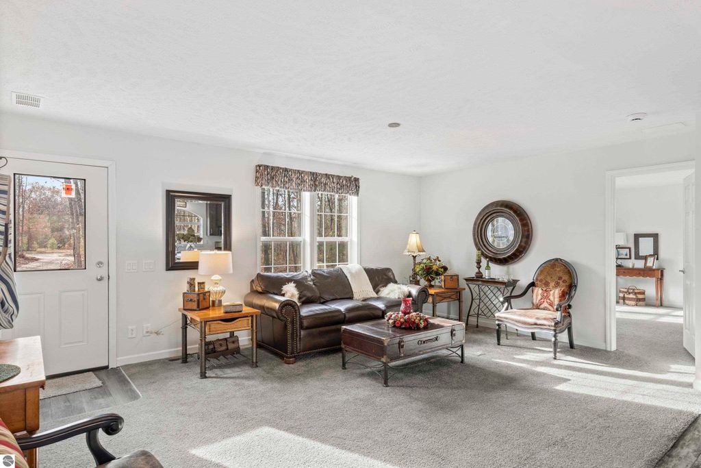 Living room of a ranch-style home at 11754 Country Acres Drive, featuring a cozy seating area with a brown leather sofa, decorative coffee table with floral arrangement, and large windows allowing natural light, set in a welcoming, move-in ready space.