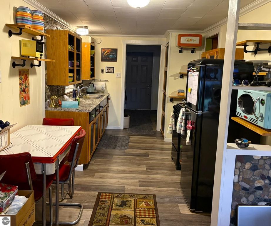 Cozy kitchen interior of a waterfront cottage in Grawn, MI, featuring wooden cabinets, a dining table with red chairs, and modern appliances, showcasing a blend of rustic charm and functionality.