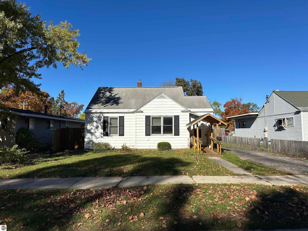 Bungalow-style home at 224 W Fifteenth Street, Traverse City, featuring a front porch, landscaped yard, and nearby residential properties, highlighting its prime downtown location.