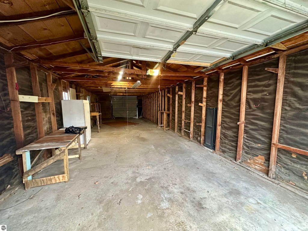 Interior view of a spacious garage at 224 W Fifteenth Street, Traverse City, featuring wooden beams, concrete flooring, and shelves, highlighting potential for storage or workspace.