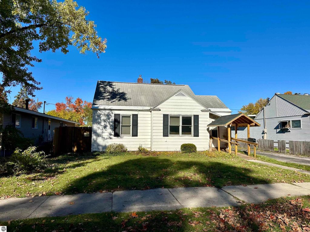 Bungalow at 224 W Fifteenth Street, Traverse City, featuring a front porch, green lawn, and nearby residential buildings, ideal for downtown living.