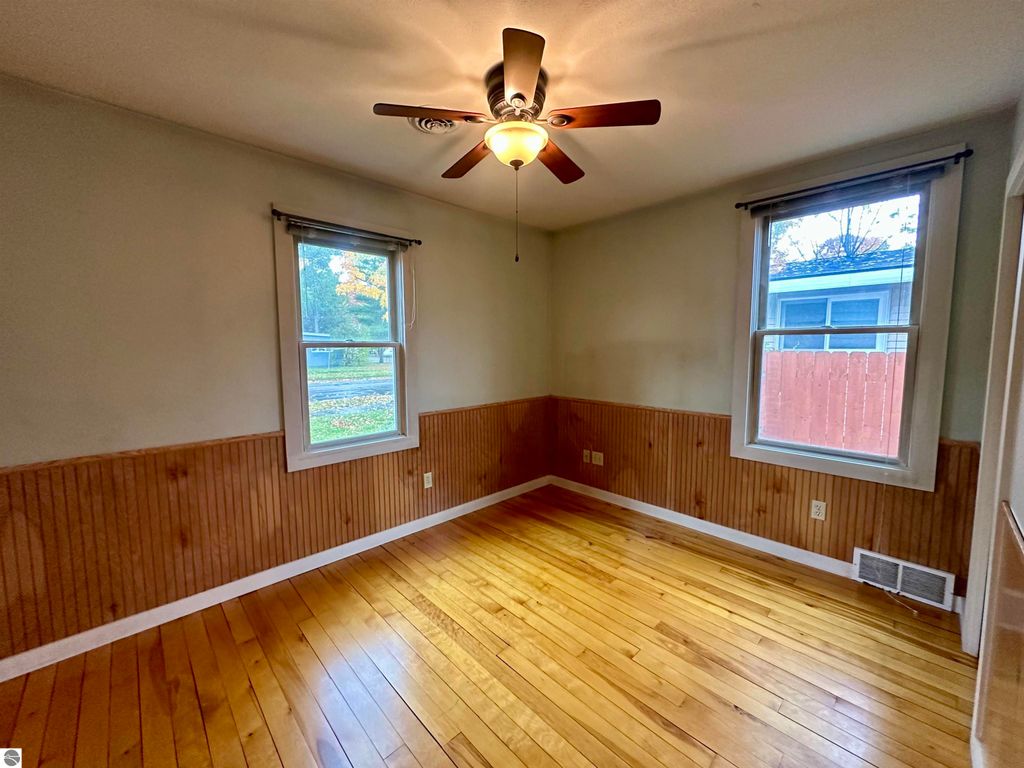 Cozy interior of bungalow at 224 W Fifteenth Street, Traverse City, featuring hardwood floors, ceiling fan, and windows providing natural light.