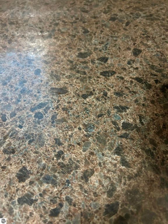 Granite countertop surface featuring a blend of brown and gray tones, showcasing a polished finish, suitable for kitchen or bathroom spaces in residential properties.