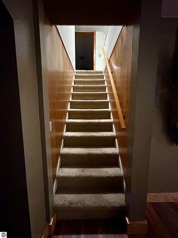Carpeted staircase leading to a well-lit upper level, showcasing the inviting interior of the home at 1007 W First Street, Tawas City, MI, ideal for families seeking space and comfort.