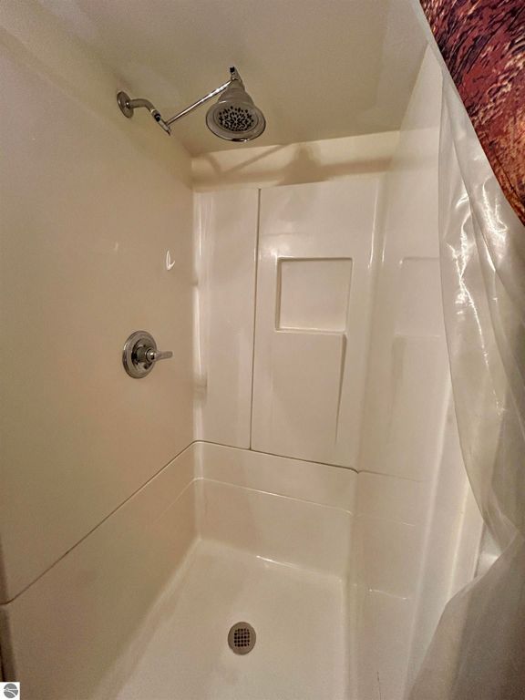 Shower stall featuring a modern showerhead, white walls, and a clean, minimalist design, suitable for the listing at 1007 W First Street, Tawas City, MI.