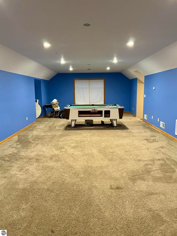 Spacious bonus room featuring a billiards table, blue walls, and plush carpet, ideal for family entertainment in a Tawas City home.