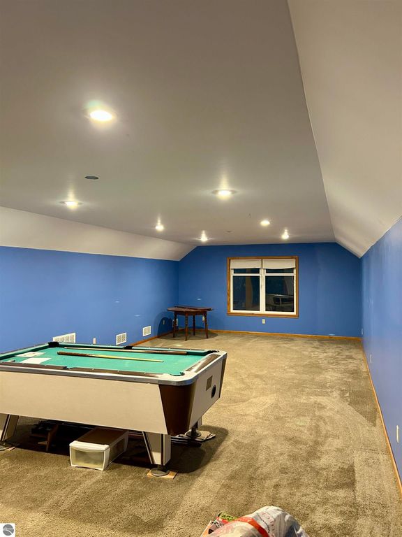 Expansive bonus room with billiards table and natural light, featuring blue walls and carpet, ideal for family entertainment at 1007 W First Street, Tawas City, MI.
