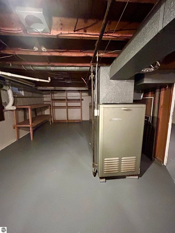 Basement interior featuring a furnace, shelving units, and concrete flooring, highlighting the functional space of the property at 1007 W First Street, Tawas City, MI.