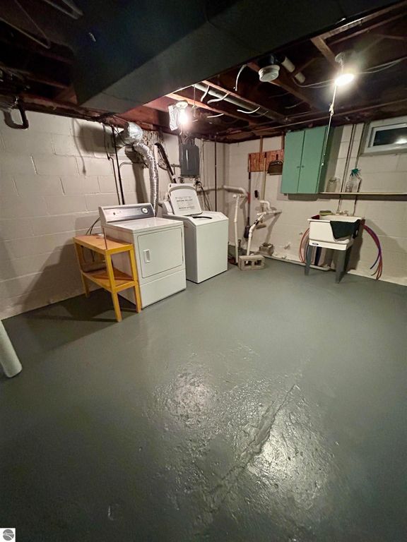 Basement laundry area featuring a washer and dryer, utility sink, and storage space, highlighting practical home amenities for the property at 1007 W First Street, Tawas City, MI.