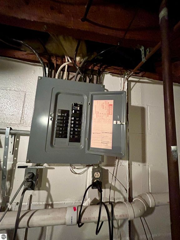 Electrical panel with multiple circuit breakers and wiring in a basement setting, showcasing home infrastructure relevant to the property at 1007 W First Street, Tawas City, MI.