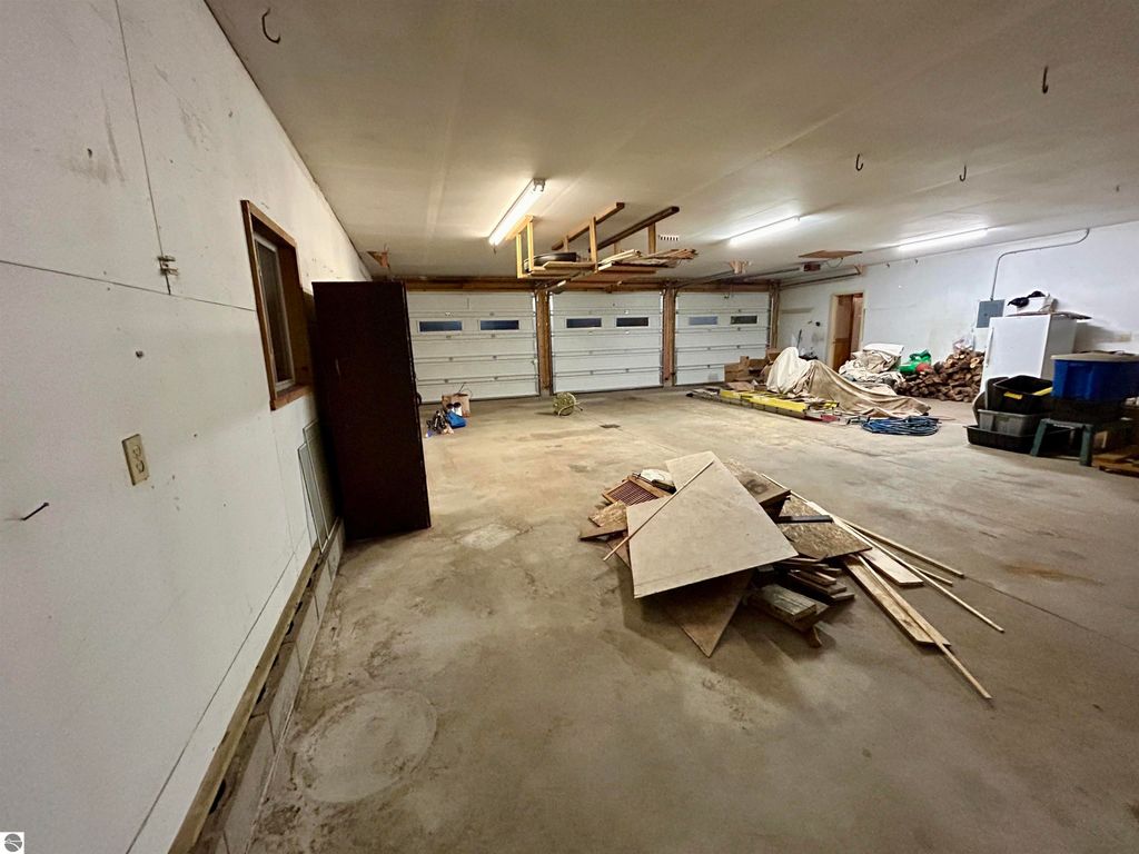 Spacious garage interior with cluttered storage, featuring two garage doors, tools, and construction materials, ideal for hobbies and storage at 1007 W First Street, Tawas City, MI.