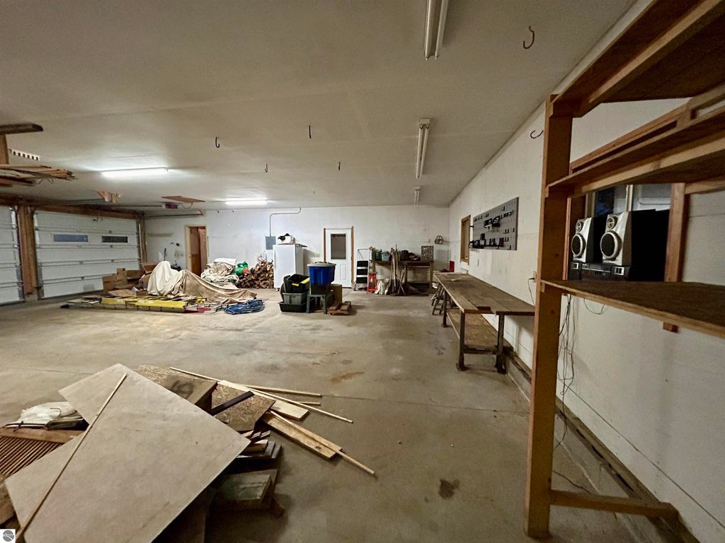 Spacious garage interior with storage shelves, workbench, and organized tools, showcasing ample space for hobbies and storage at 1007 W First Street, Tawas City, MI.