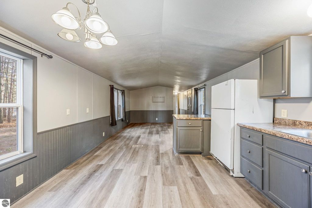 Interior view of a move-in ready home featuring an open layout, modern appliances, new flooring, and ample natural light from large windows, suitable for potential buyers in Cadillac, MI.
